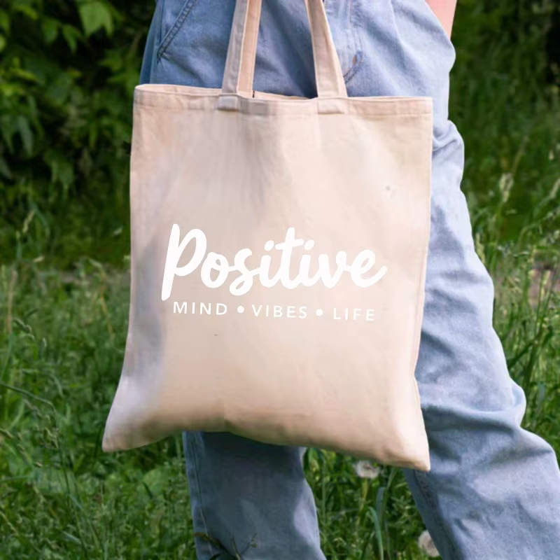 Sac fourre-tout en toile de couleur crème avec slogan vivant mindset positif imprimé sur le devant